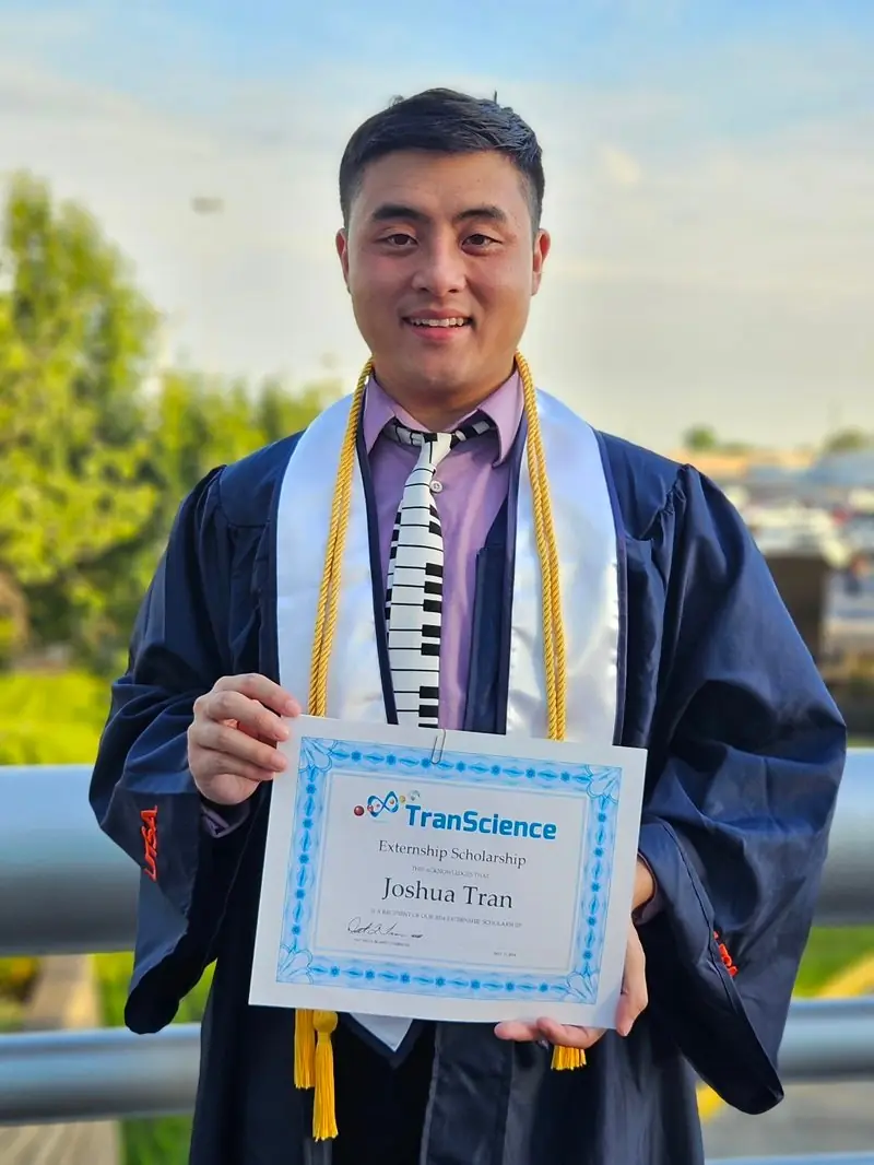 Joshua Tran in a graduation gown holding his externship certificate