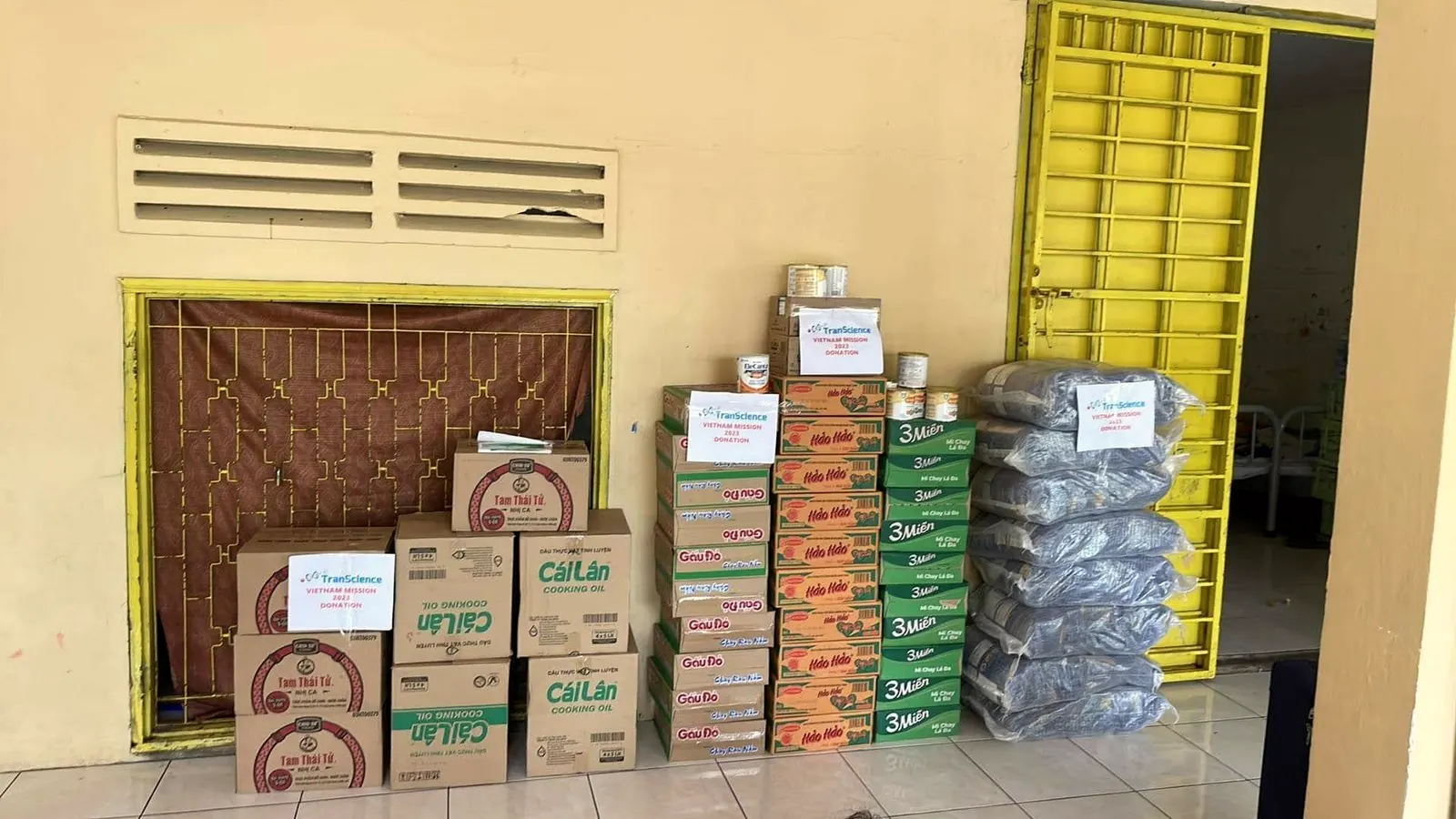 Cases of rice, oil, noodles and formula stacked against a pagoda wall