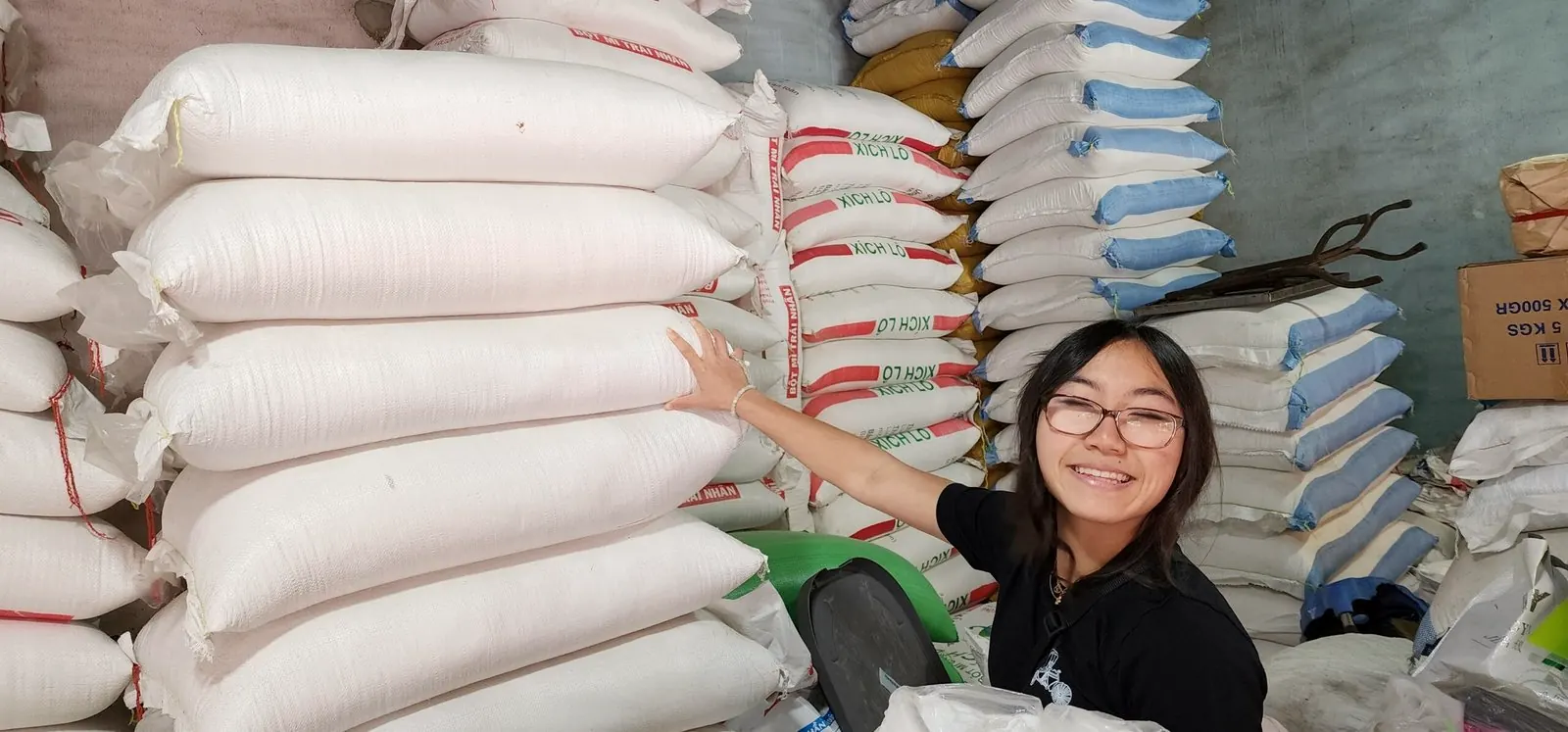 Rilina Tran beside a tall stack of rice sacks