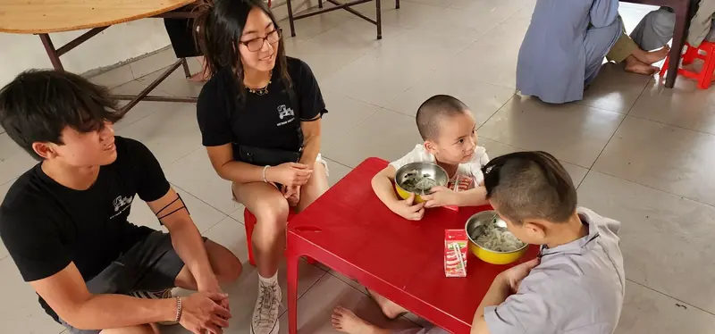Rilina and Dylan share a meal with young children