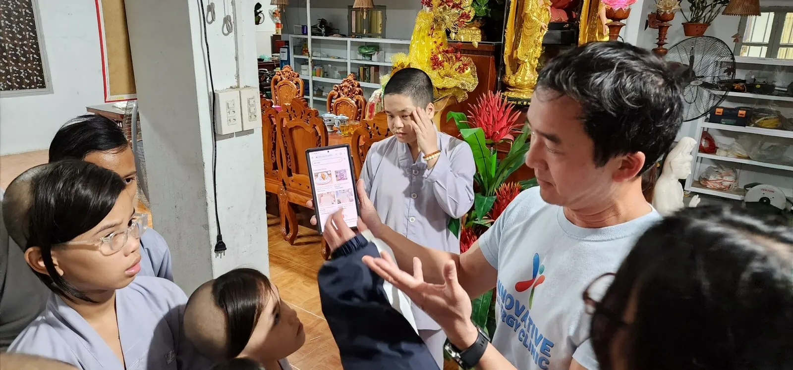Dr. Dat Tran shows a phone to children and a monk