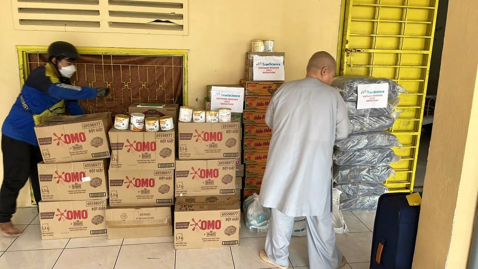 A monk and a helper stack boxes of donated food at Tu Hanh Pagoda