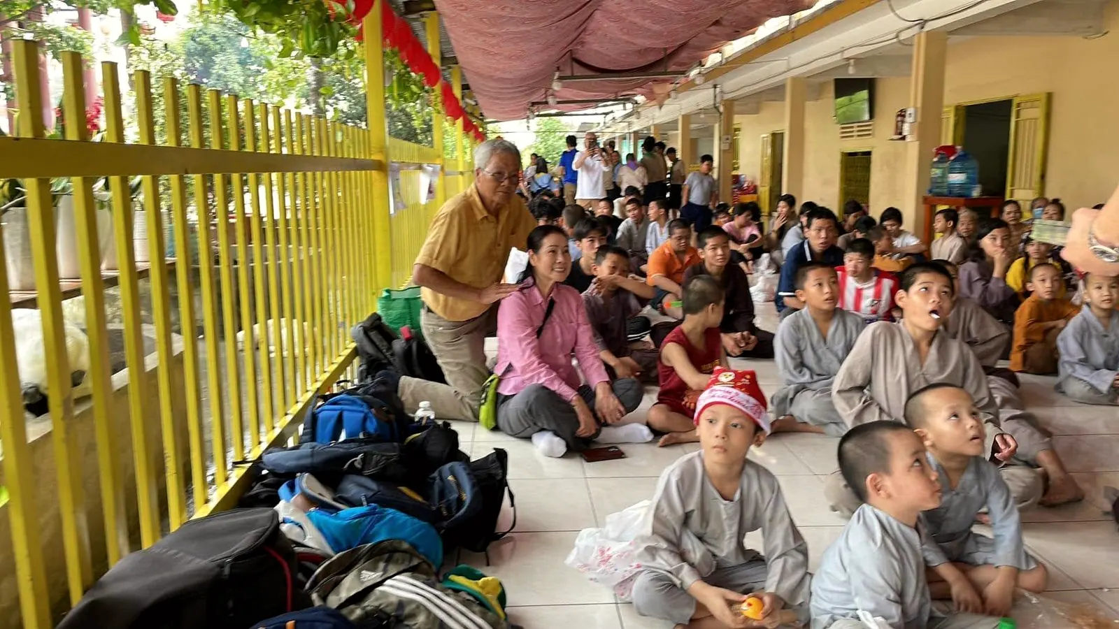 Children and monks sit on a pagoda floor waiting to share a snack
