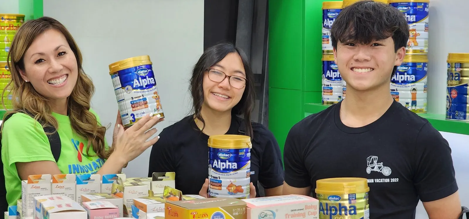 Holly, Rilina and Dylan hold cans of infant formula in a store