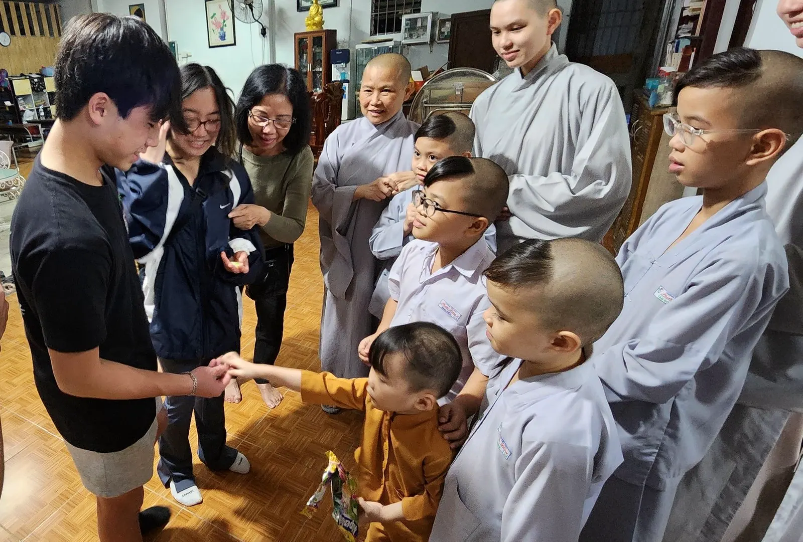 A young monk hands candy to Dylan Tran while other children watch